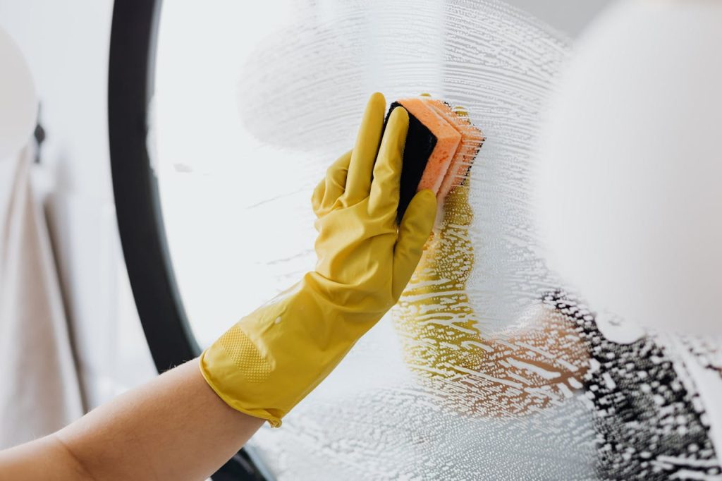 Mastering the First Impression: Your intriguing post title goes here Anonymous person in yellow rubber gloves using simple sponge for cleaning mirror in bathroom
